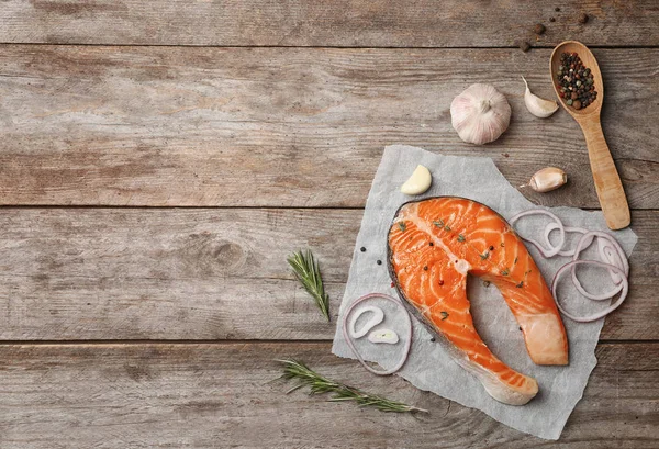 Fresh raw salmon steak with seasonings on wooden background, top view — Stock Photo, Image