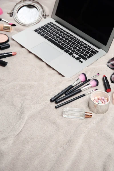 Composition with laptop and makeup products for woman on fabric