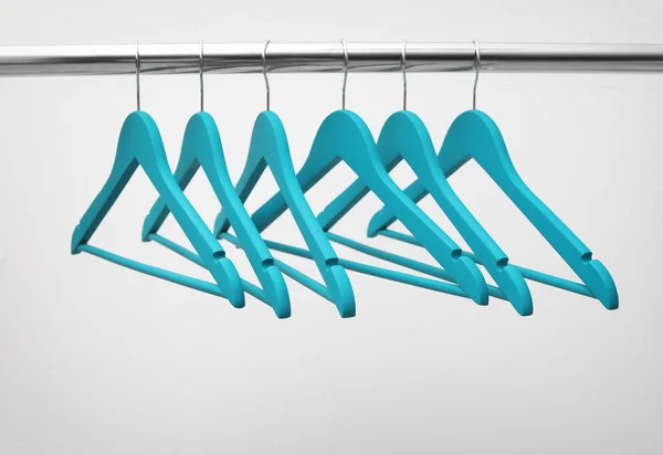 Clothes hangers on metal rail against light background — Stock Photo, Image