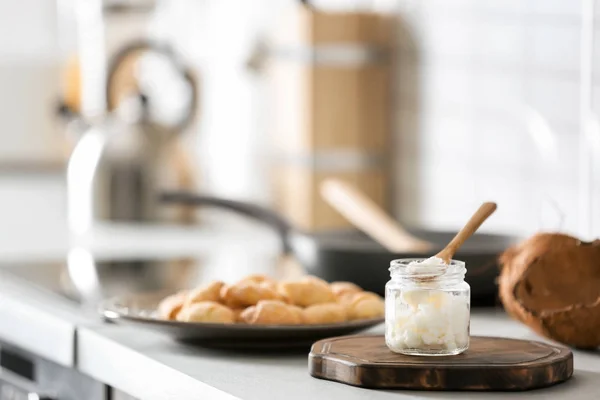 Frasco com óleo de coco na mesa na cozinha. Cozinhar saudável — Fotografia de Stock