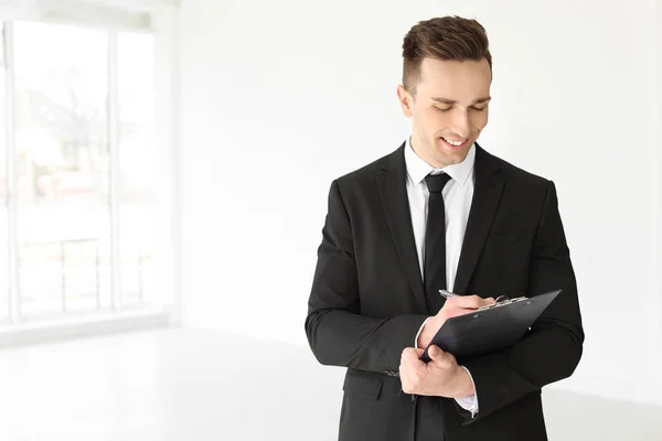 Male real estate agent with clipboard indoors Stock Image
