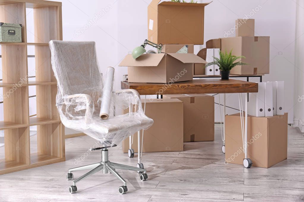 Armchair and carton boxes with stuff in room. Office move concept
