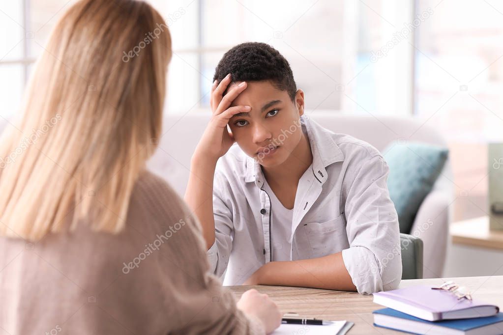 Young female psychologist working with teenage boy in office