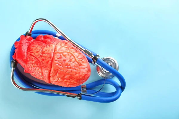 Стетоскоп і модель серця на кольоровому фоні. Концепція серцевого нападу — стокове фото