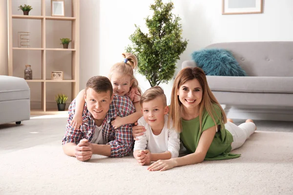 Lycklig familj liggande på mysiga mattan hemma — Stockfoto