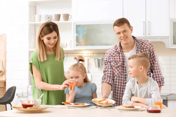Rodiče a roztomilé malé děti snídat s chutné toastový chléb u stolu v kuchyni — Stock fotografie