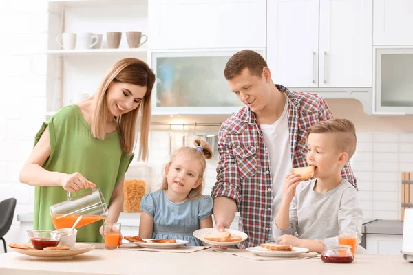 Föräldrar och söta små barn med frukost med läckra rostat bröd vid bordet i köket — Stockfoto