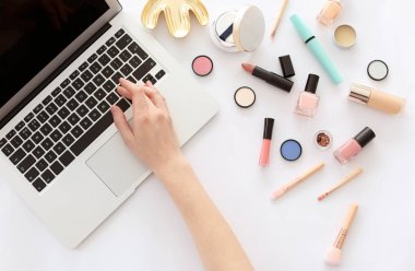 Genç kadın masada dizüstü kullanarak makyaj ürünleri ile. Güzellik blogger