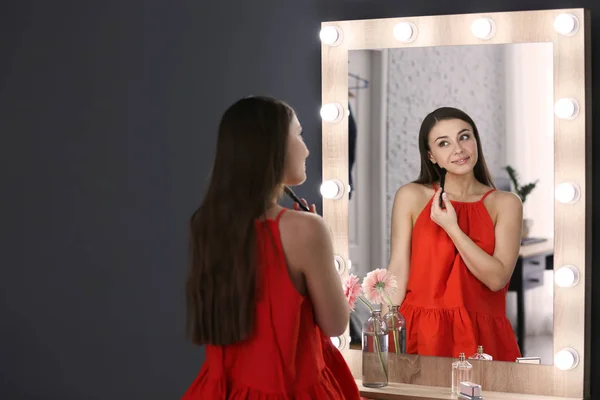 Joven hermosa mujer aplicando maquillaje cerca del espejo — Foto de Stock