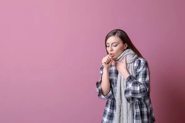 Young woman coughing on color background