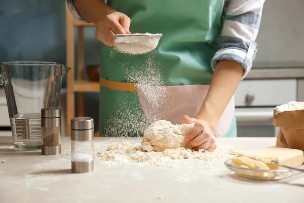 Mujer rociando la harina sobre la masa en la mesa en la cocina —  Fotos de Stock