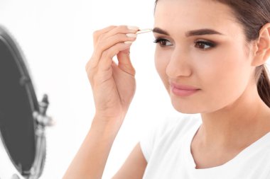 Genç kadın kaş cımbız ile kapalı koparma