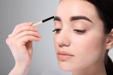 Güzel bir kadın ile mükemmel kaşlar hafif arka plan üzerinde makyaj uygulamak