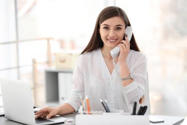 İş yerinde telefonla konuşan genç bir kadın.