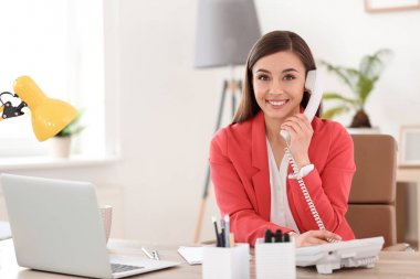 İş yerinde telefonla konuşan genç bir kadın.