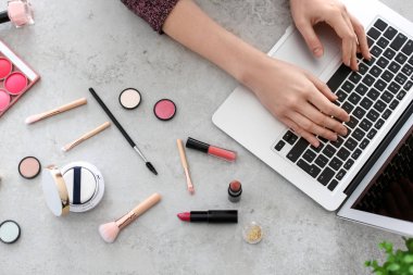 Genç kadın masada dizüstü kullanarak makyaj ürünleri ile. Güzellik blogger