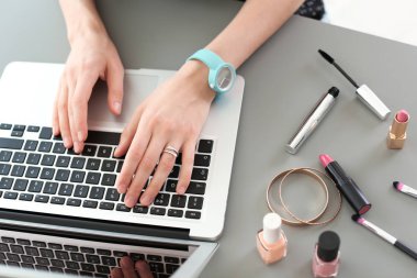 Genç kadın masada dizüstü kullanarak makyaj ürünleri ile. Güzellik blogger