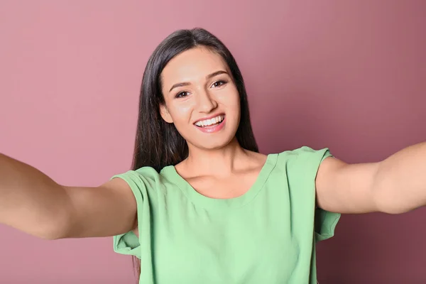 Young beautiful woman taking selfie against color background — Stock Photo, Image