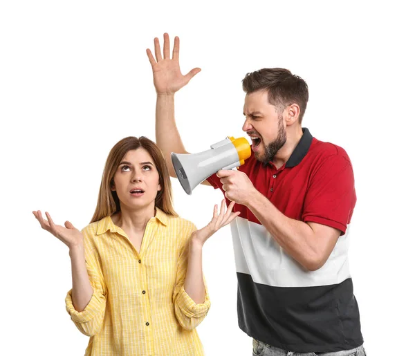Young man with megaphone shouting at woman on white background — Stock Photo, Image