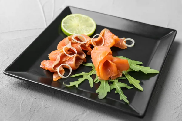 Teller mit frisch geschnittenem Lachsfilet, Zitrone und Rucola auf dem Tisch — Stockfoto