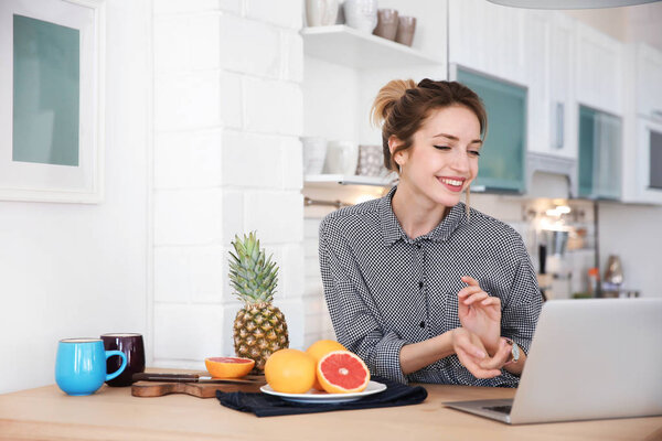 Young blogger with fruits and laptop on kitchen