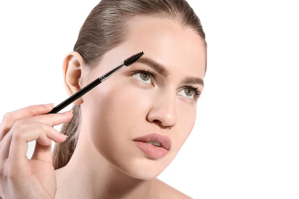 Beautiful woman with perfect eyebrows applying makeup on light background — Stock Photo, Image