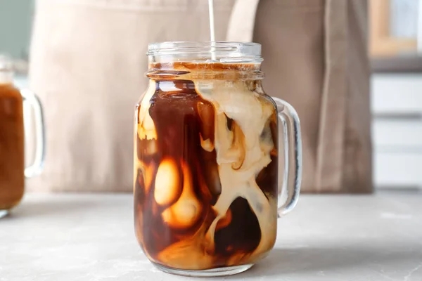 Pouring milk into mason jar with cold brew coffee on table — Stock Photo, Image