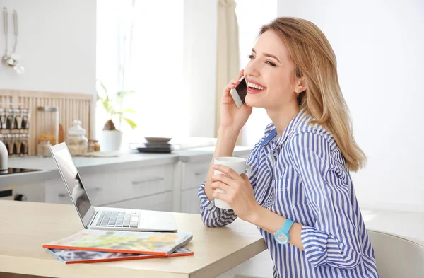 Genç kadın kapalı dizüstü bilgisayar kullanırken telefonda konuşurken — Stok fotoğraf