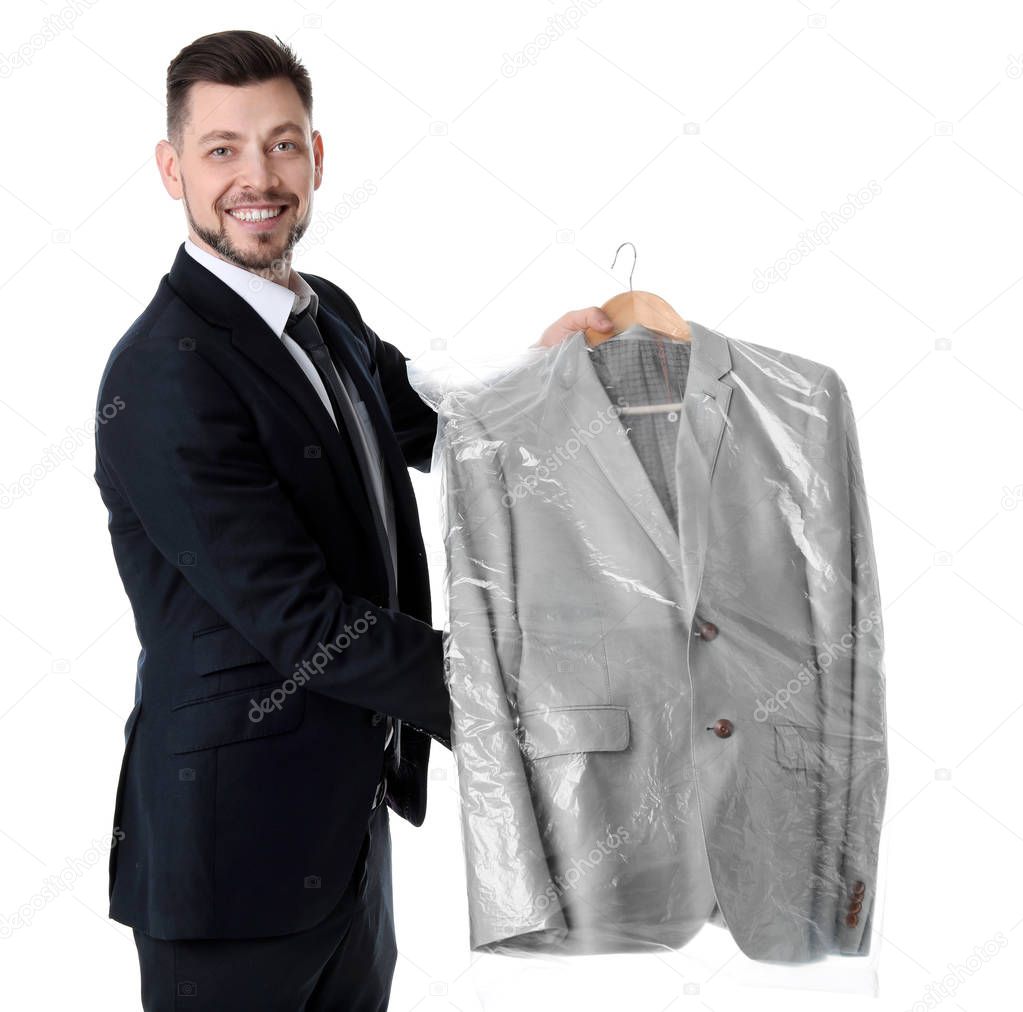 Young businessman holding hanger with jacket in plastic bag on white background. Dry-cleaning service
