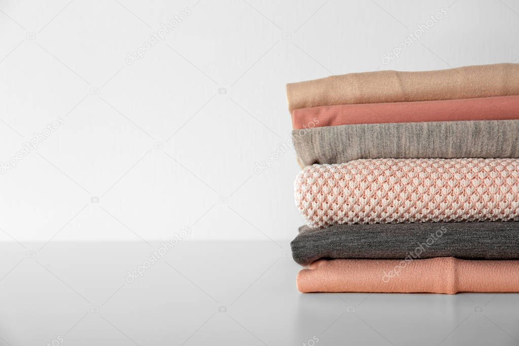 Stack of clothes on table against light background