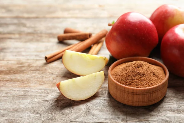 Verse appels met kaneelstokjes en poeder op houten tafel — Stockfoto