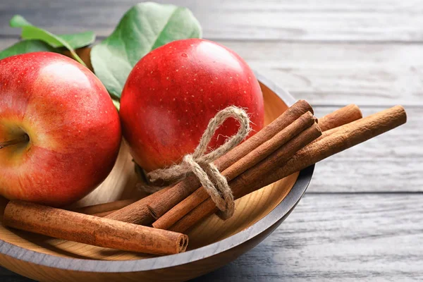 Verse appels en kaneelstokjes in kom, close-up — Stockfoto