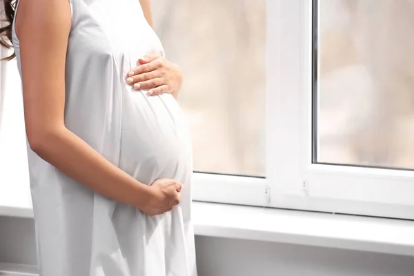 Mooie zwangere vrouw in de buurt van raam thuis — Stockfoto