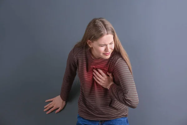 Fiatal nő szívroham szürke háttér — Stock Fotó
