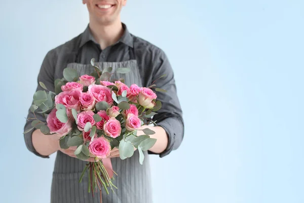 Fleuriste masculin tenant bouquet de belles fleurs sur fond clair — Photo