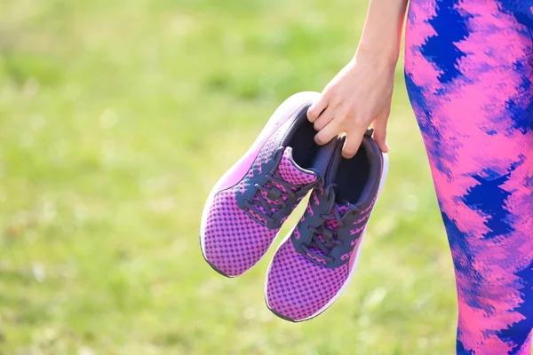 Young woman with training shoes outdoors, closeup