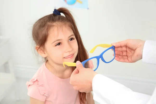 Kvinnliga ögonläkare att sätta glasögon på liten flicka i kliniken — Stockfoto