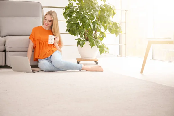 Молодая женщина с ноутбуком сидит дома на полу — стоковое фото