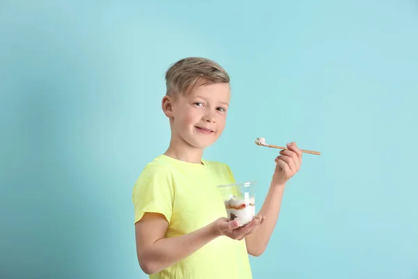 Liten pojke med yoghurt på färgbakgrund — Stockfoto