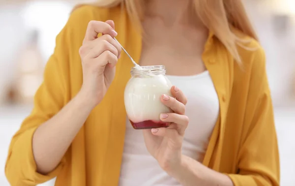 Ung kvinne med yoghurt på utydelig bakgrunn – stockfoto