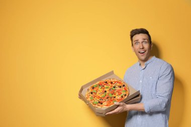 Renk arka plan üzerinde lezzetli pizza ile çekici bir genç adam
