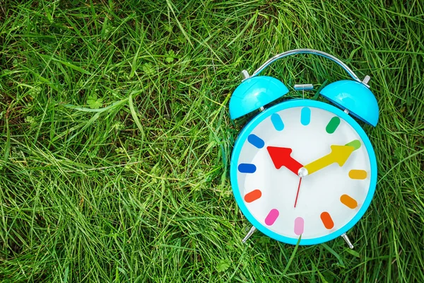 Relógio despertador na grama verde, ao ar livre. Conceito de mudança temporal — Fotografia de Stock