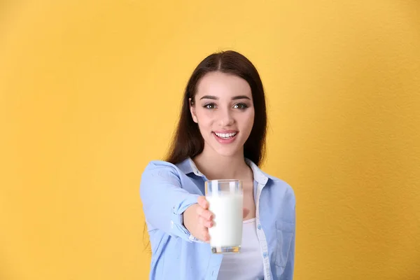 Красивая молодая женщина пьет молоко на цветном фоне — стоковое фото
