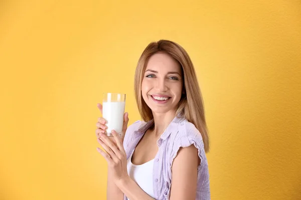 Bella giovane donna che beve latte su sfondo di colore — Foto Stock