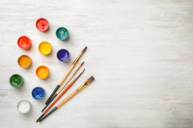 Farklı boyalar ve fırçalar ahşap arka plan üzerinde düz yatıyordu kompozisyonu. Renk paleti