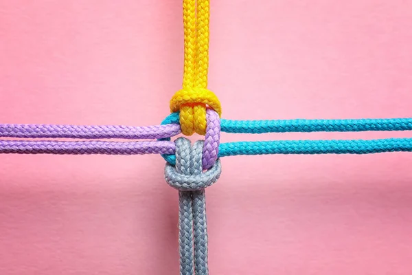 Différentes cordes attachées ensemble avec noeud sur fond de couleur. Concept d'unité — Photo