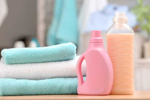 Stos czyste ręczniki i butelki z detergentem na stole — Zdjęcie stockowe