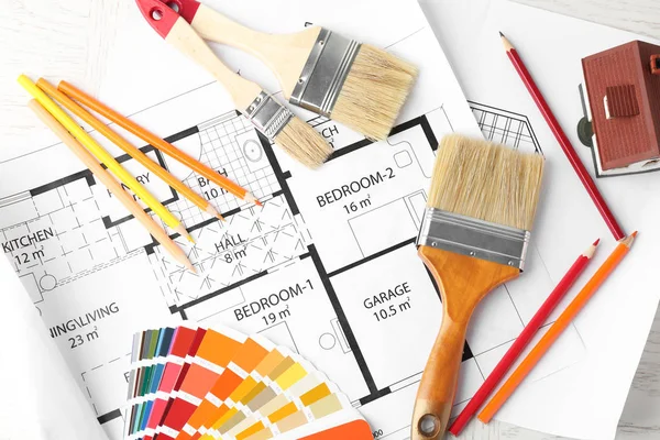 Plochá laických složení s barevnou paletu, plán domu a štětce na stole — Stock fotografie
