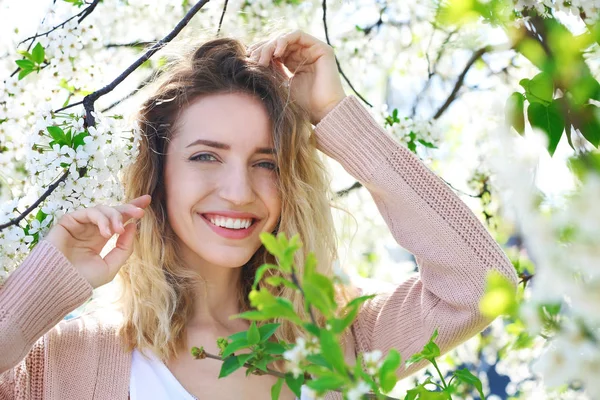 Atractiva joven posando cerca de un árbol en flor en el soleado día de primavera —  Fotos de Stock