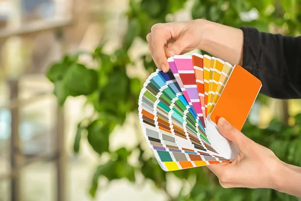 Designer feminino segurando amostras de paleta de cores em fundo embaçado — Fotografia de Stock
